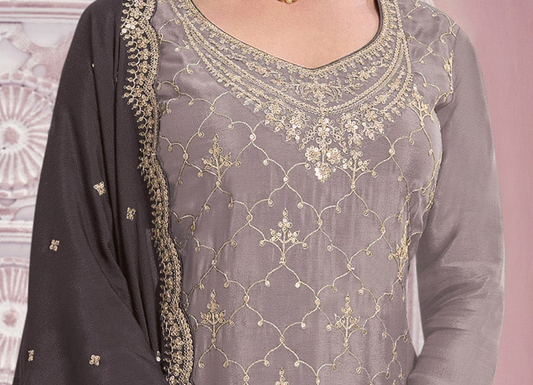 A close-up of a woman wearing a gray georgette salwar kameez suit with intricate gold embroidery and a matching dark gray dupatta.