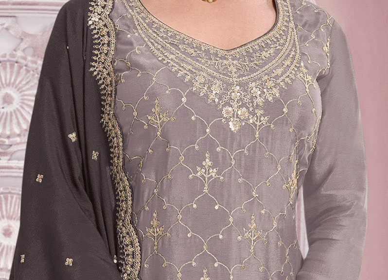 A close-up of a woman wearing a gray georgette salwar kameez suit with intricate gold embroidery and a matching dark gray dupatta.