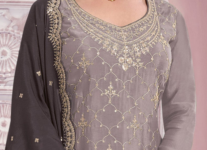 A close-up of a woman wearing a gray georgette salwar kameez suit with intricate gold embroidery and a matching dark gray dupatta.