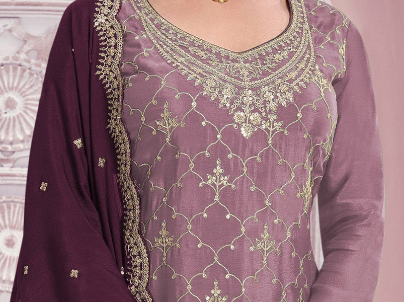 A close-up of a traditional Indian salwar kameez outfit in dusty purple with intricate gold embroidery on the neckline and body, paired with a matching purple dupatta featuring gold border detailing.