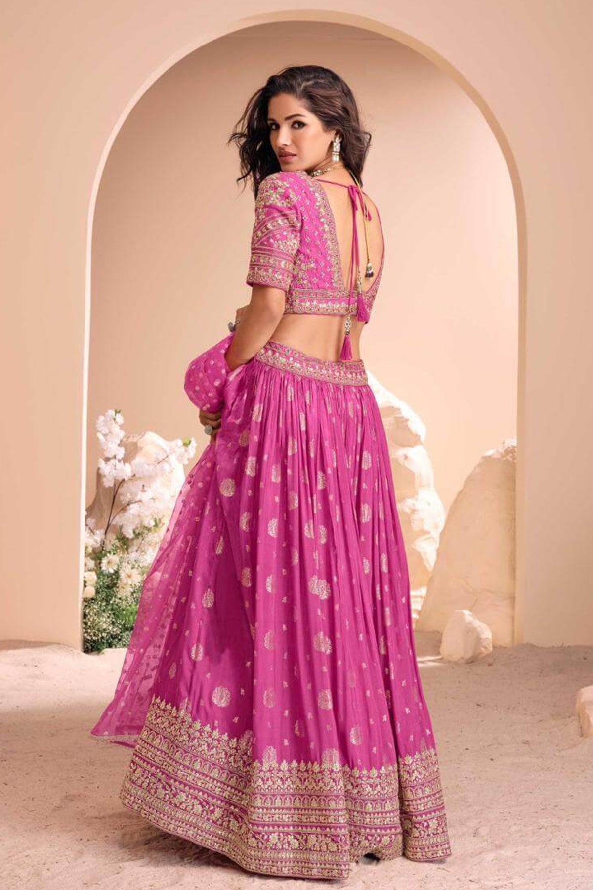 Women’s pink cropped choli with intricate zari embroidery, V neck and short sleeves paired with flared lehenga and net dupatta set